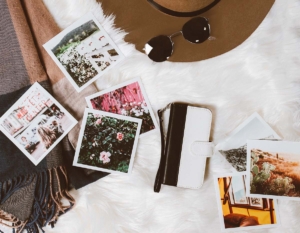 A perfect flat lay with photos, hat, and sunglasses on a white furry background