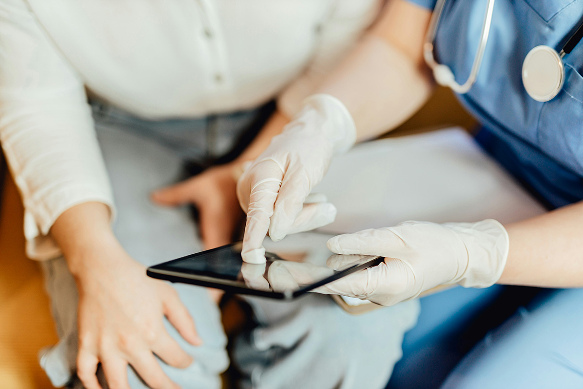 A doctor holding a tablet with a patient, thematically related to recent updates by Google Ads for its Healthcare and Medicine policy